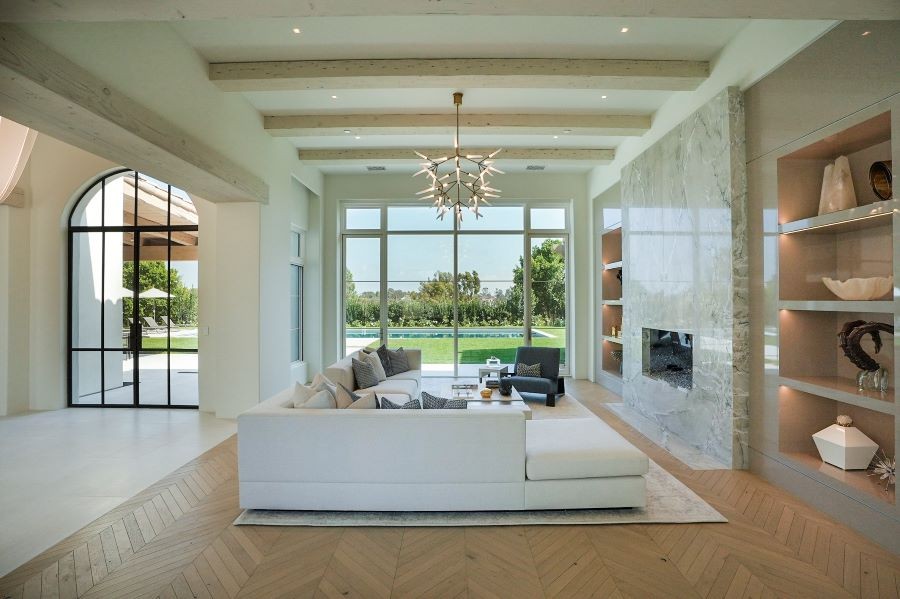 A living room with in-ceiling speakers and picture windows looking out to the pool.