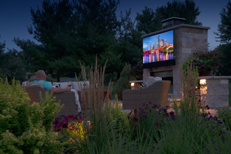 People watching a movie in their backyard at dusk on a Séura outdoor TV.