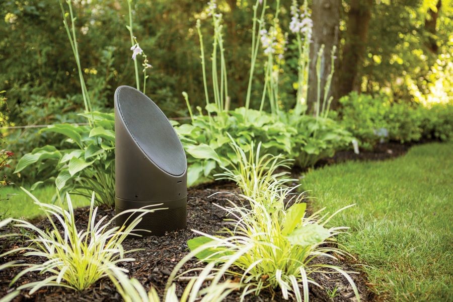 A Coastal Source Bollard speaker amidst grass and landscape.