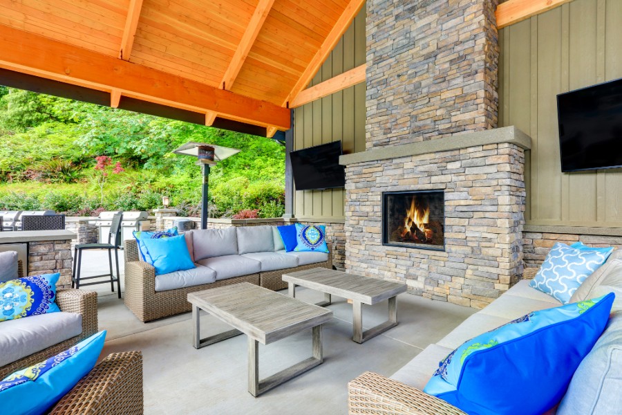 Relaxing patio with furniture, fireplace, and TVs.