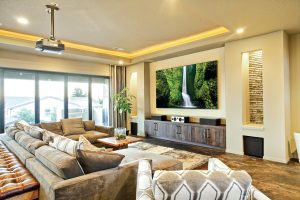 A media room in luxury home with a high-performance AV system that includes a projector, high-end speakers, and plush couches.