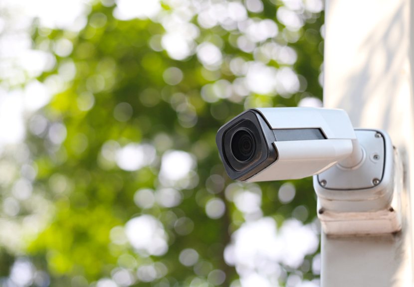 A security camera with a white casing installed in the outdoor area of a home