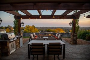 Outdoor patio at sunset with two tables next to a grill and a blazing fire pit