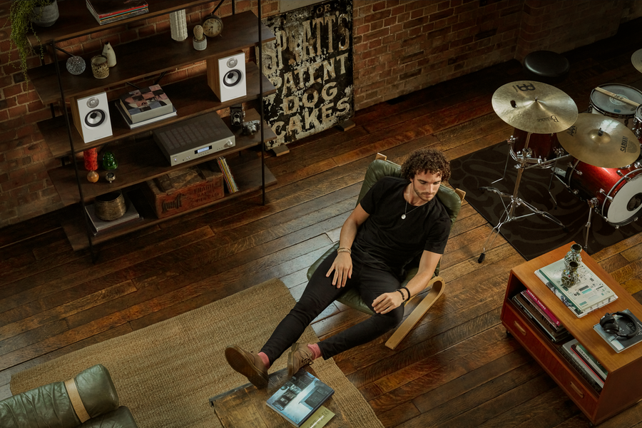 A man sits in a modern living room listening to music with Bowers & Wilkins speakers.