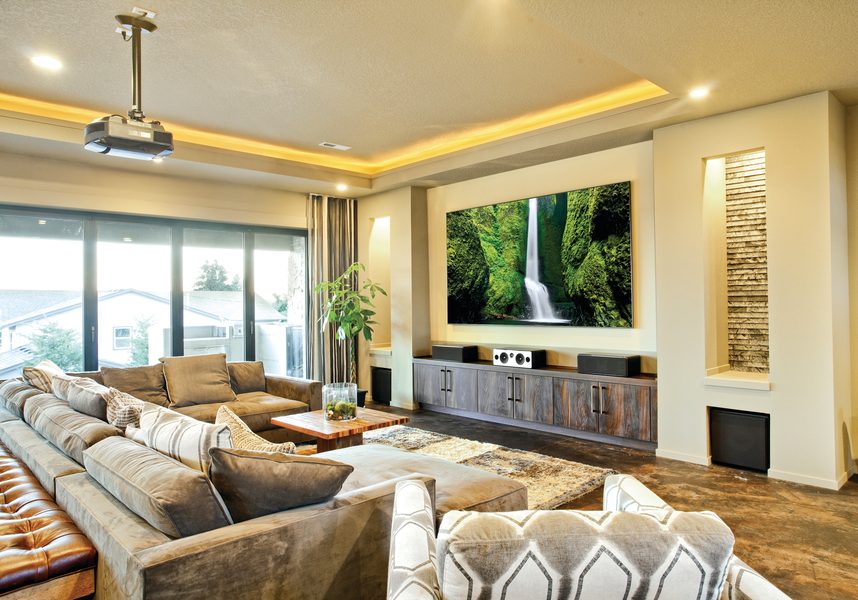 A media room in luxury home with a high-performance AV system that includes a projector, high-end speakers, and plush couches.