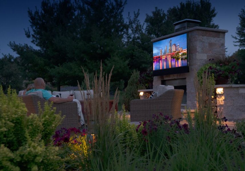 People watching a movie in their backyard at dusk on a Séura outdoor TV.