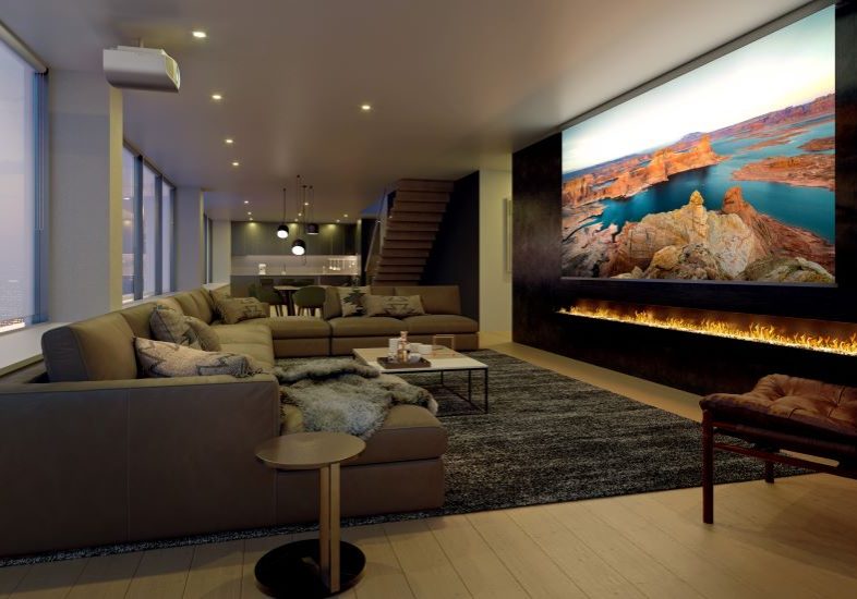 A media room with a Sony projector, sectional, and large movie screen above a fireplace.
