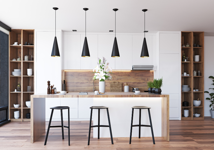 A beautiful, well-lit kitchen with three stools placed at an island under four modern light fixtures.