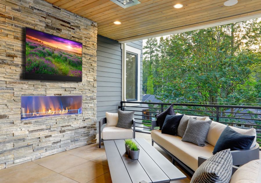 A patio with an outdoor Seura TV above a fireplace and in-ceiling speakers.