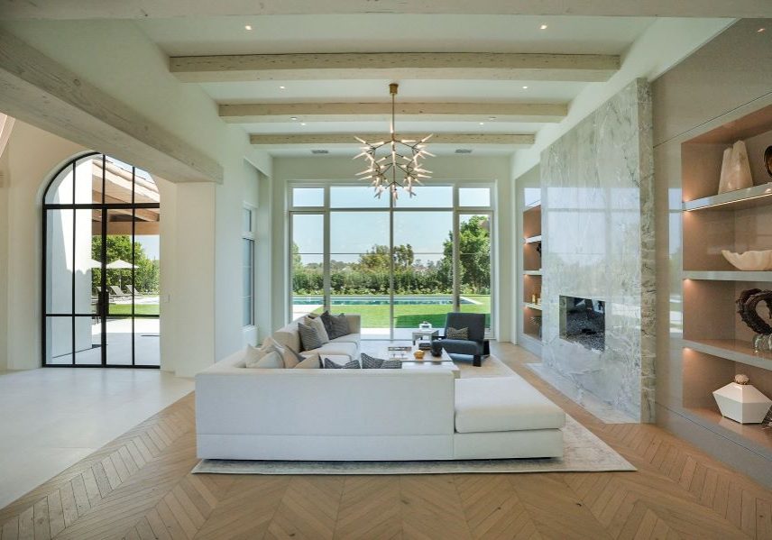 A living room with in-ceiling speakers and picture windows looking out to the pool.